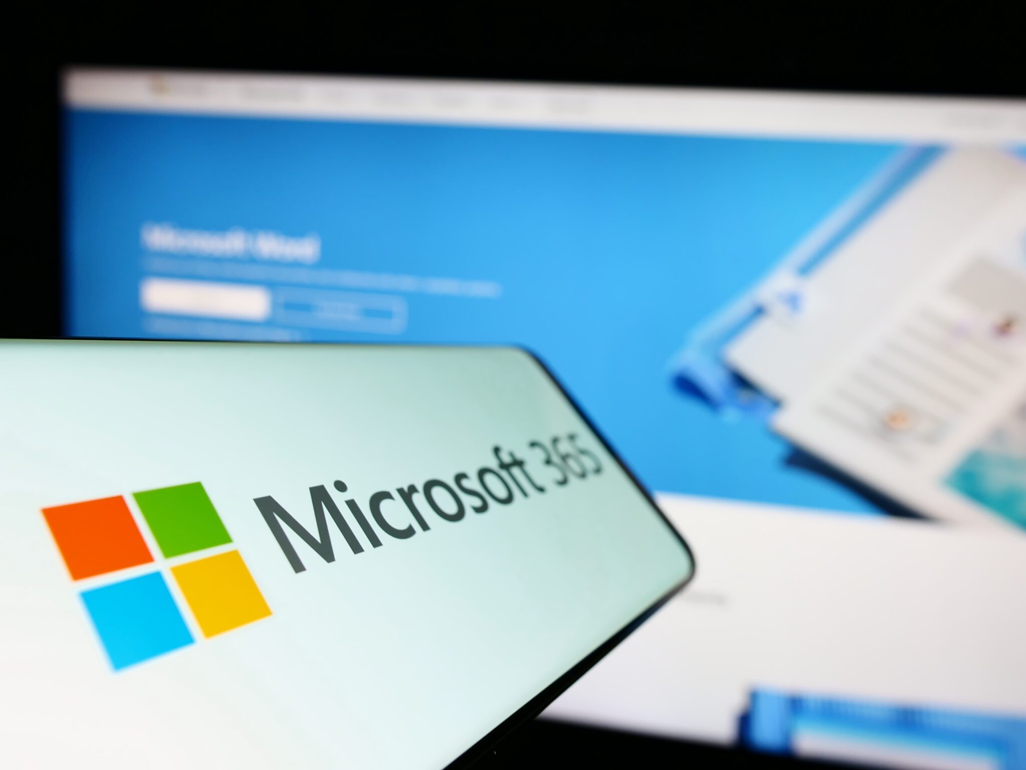 Microsoft 365 logo on a phone with a desktop in the background